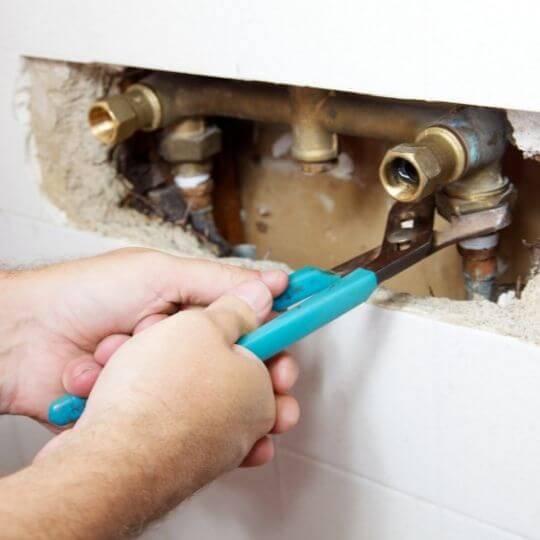 plumber_fixing_leak_behind_the_wall.jpeg